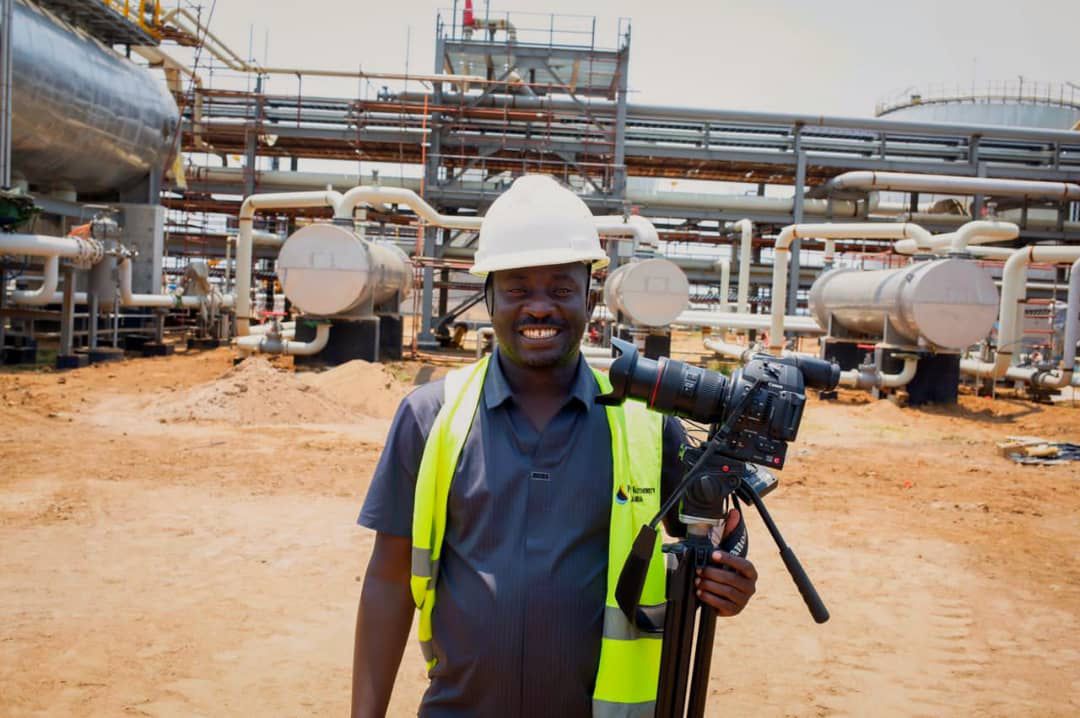 Nelson Kimbugwe, a video journalist stands infront of the central processing facility at the kingfisher oil project